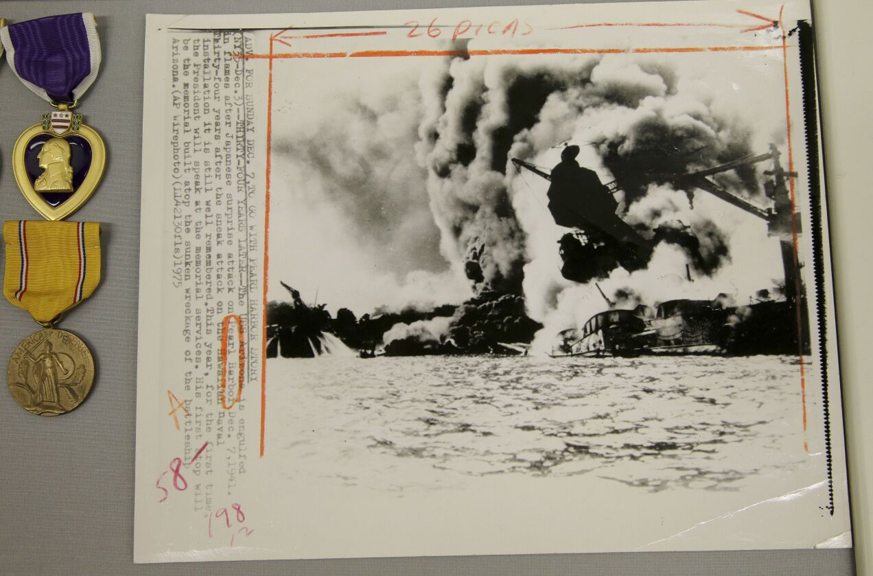 A wire transmission of a historic Dec. 7, 1941 Associated Press photo showing the battleship USS Arizona in flames after being bombed by Japanese aircraft, rests next to medals as part of an exhibit at The Museum of World War II, Boston, in Natick, Mass.